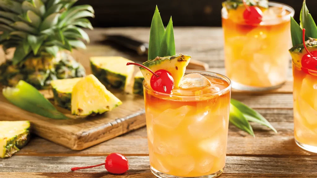 drei Gläser mit fruchtigen Cocktail mit Ananas und Kirschen verziert