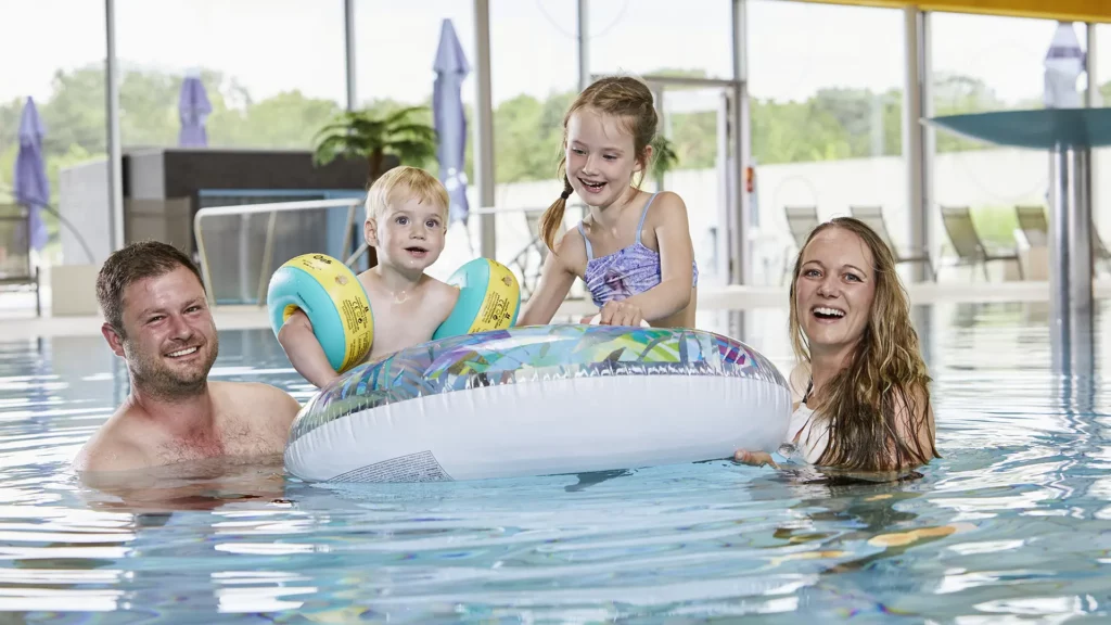 Eine Familie mit Kindern spielt im Wasser mit einem großem Schwimmring