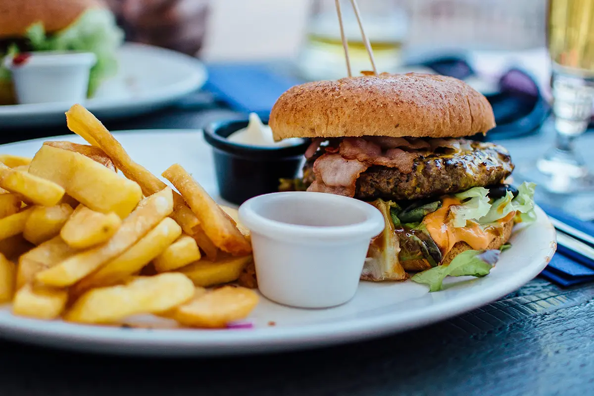 Ein Burger mit Pommes angerichtet mit Dip auf einem Teller