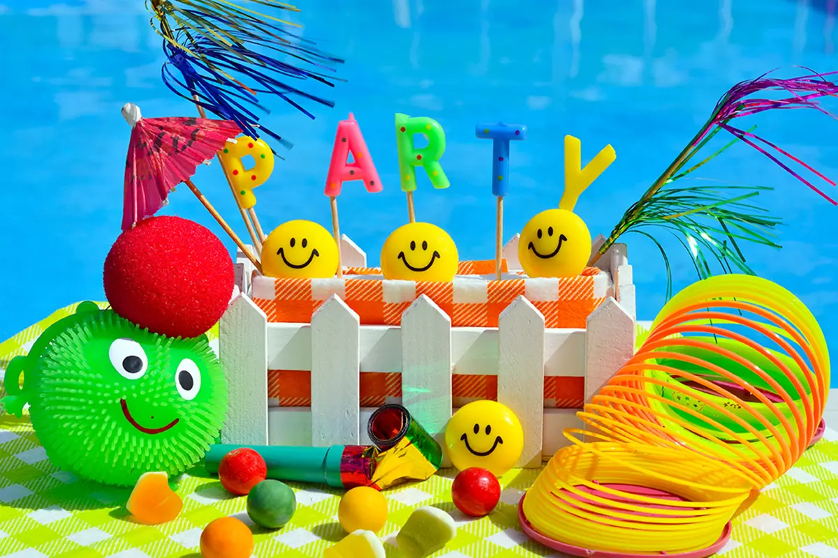 Eine Nahaufnahme mit verschiedenen Spielzeugen und den Schriftzug Party im sommerlichen Farben